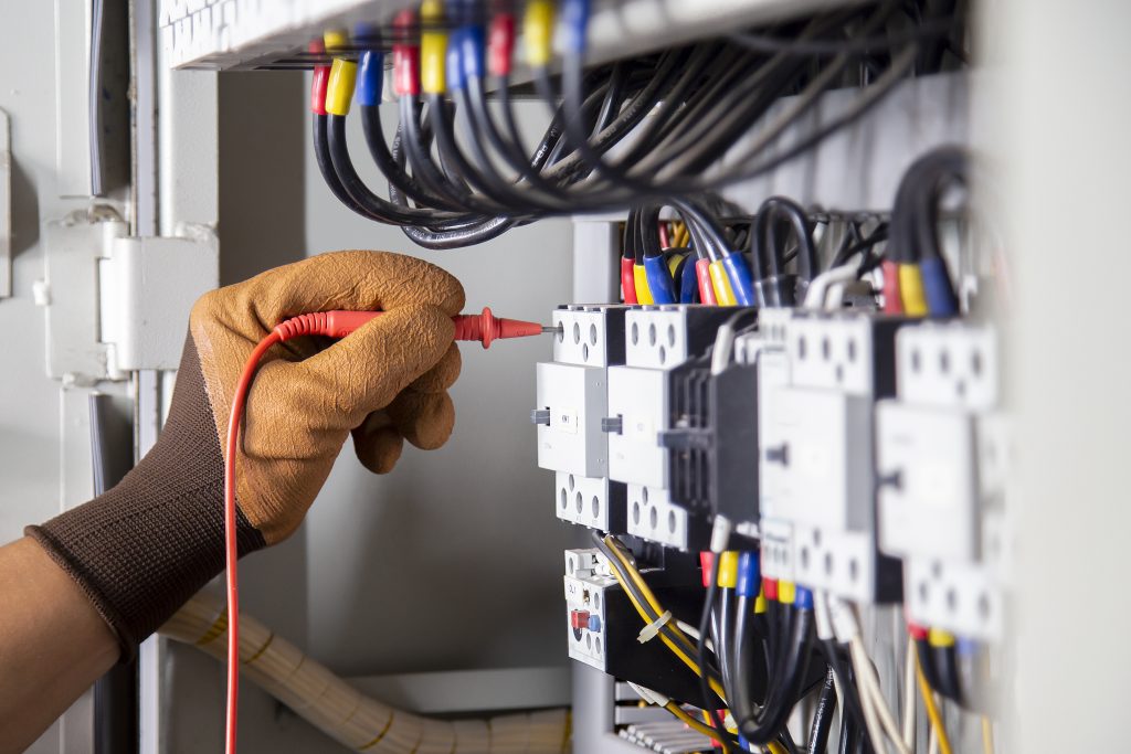Engenheiro elétrico verifica sistema elétrico medindo com multímetro, destacando cuidados de segurança e explicando o que é ESD na proteção contra descargas eletrostáticas.