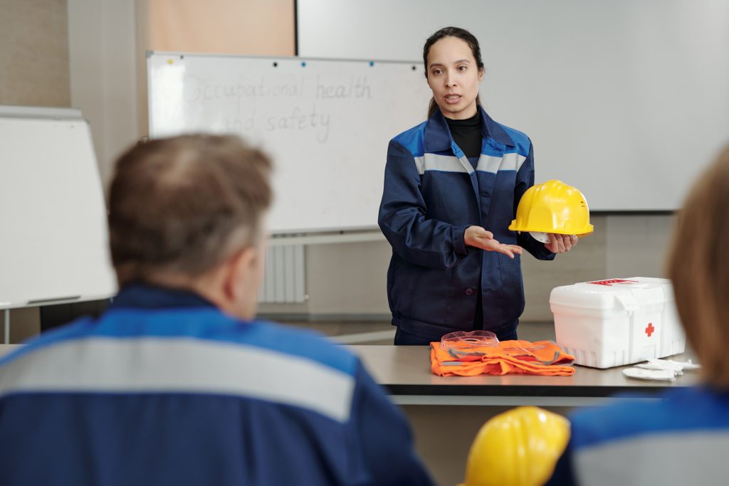 Mulher usando equipamentos de segurança no trabalho, enquanto ministra atividade prática de treinamento de segurança.