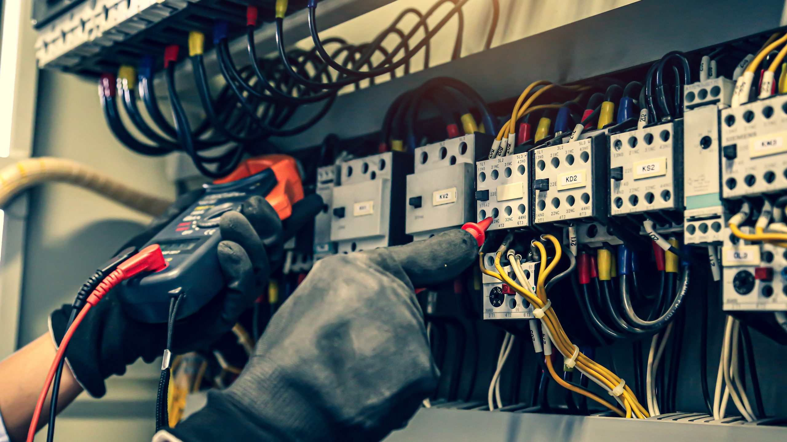 Close-up de mão de engenheiro elétrico utilizando equipamento de medição para verificação de eletricidade, representando práticas seguras e a importância de entender o que é ESD.